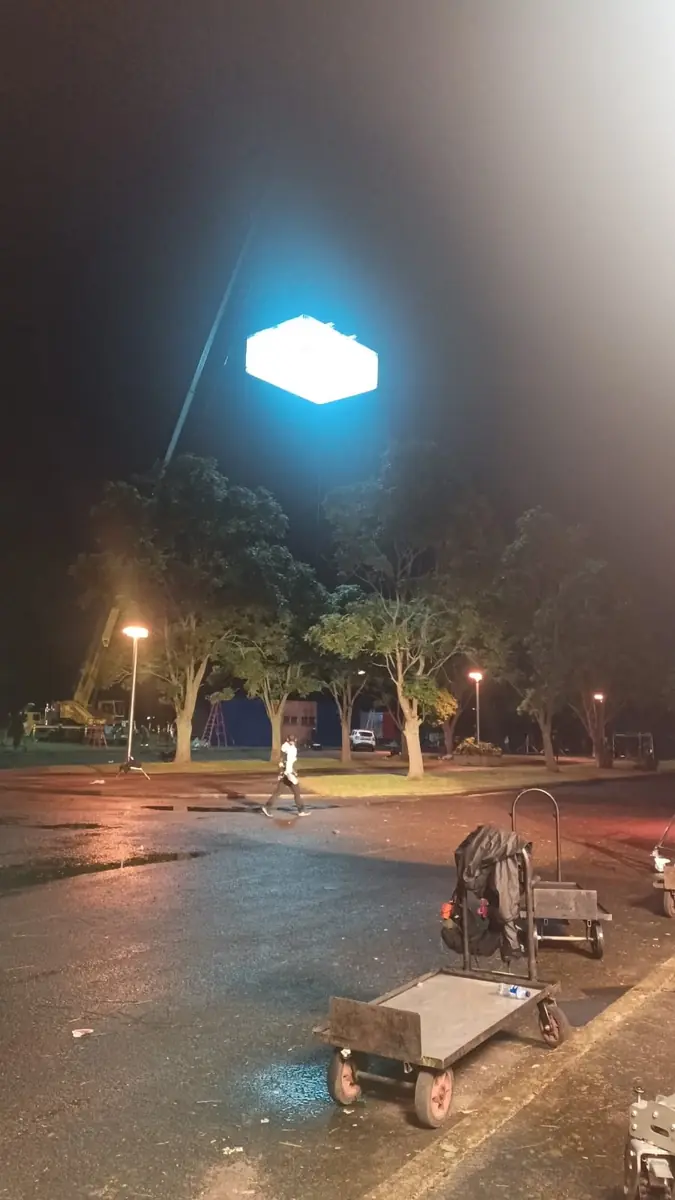 Grúa sosteniendo un globo de luz sobre un parque durante un rodaje nocturno