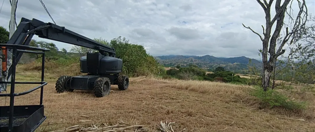 Manlift telescópico negro en una locación rural con montañas al fondo