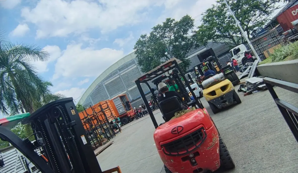 Montacargas descargando equipos frente a un coliseo