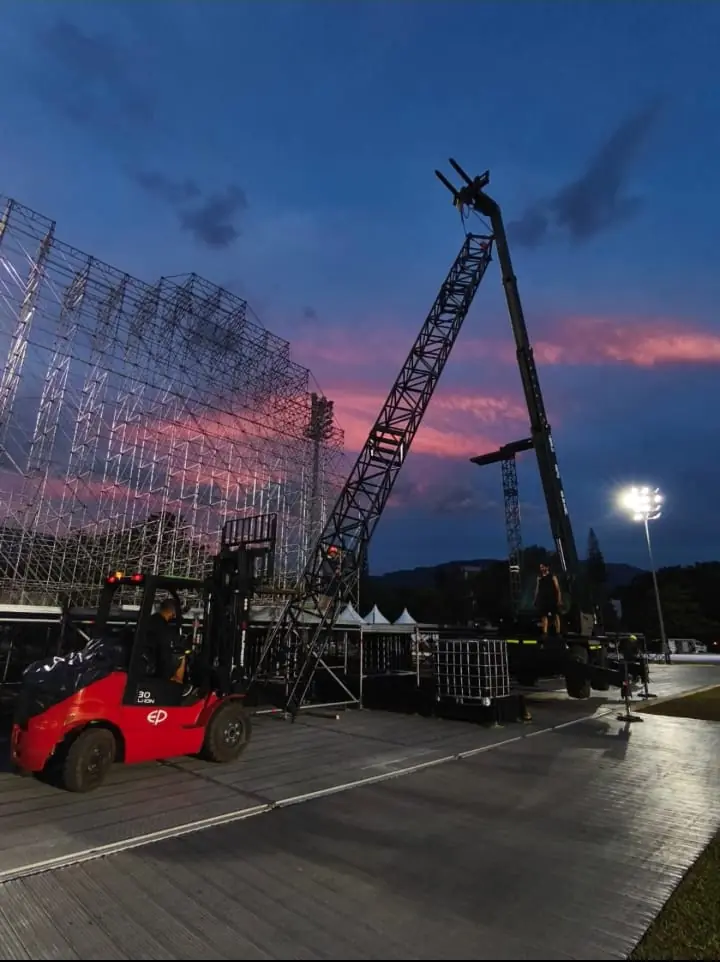 Montacarga y telehandler en el montaje de una tarima al atardecer