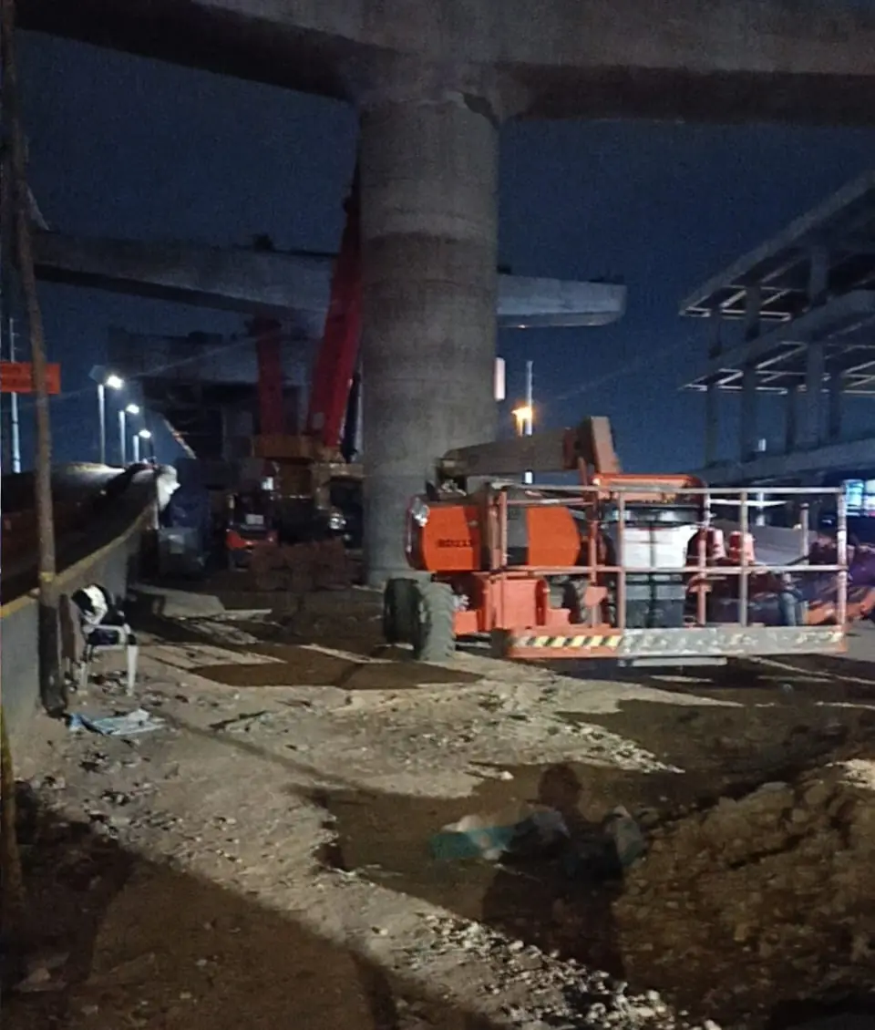 Manlift en turno nocturno bajo un viaducto en construcción