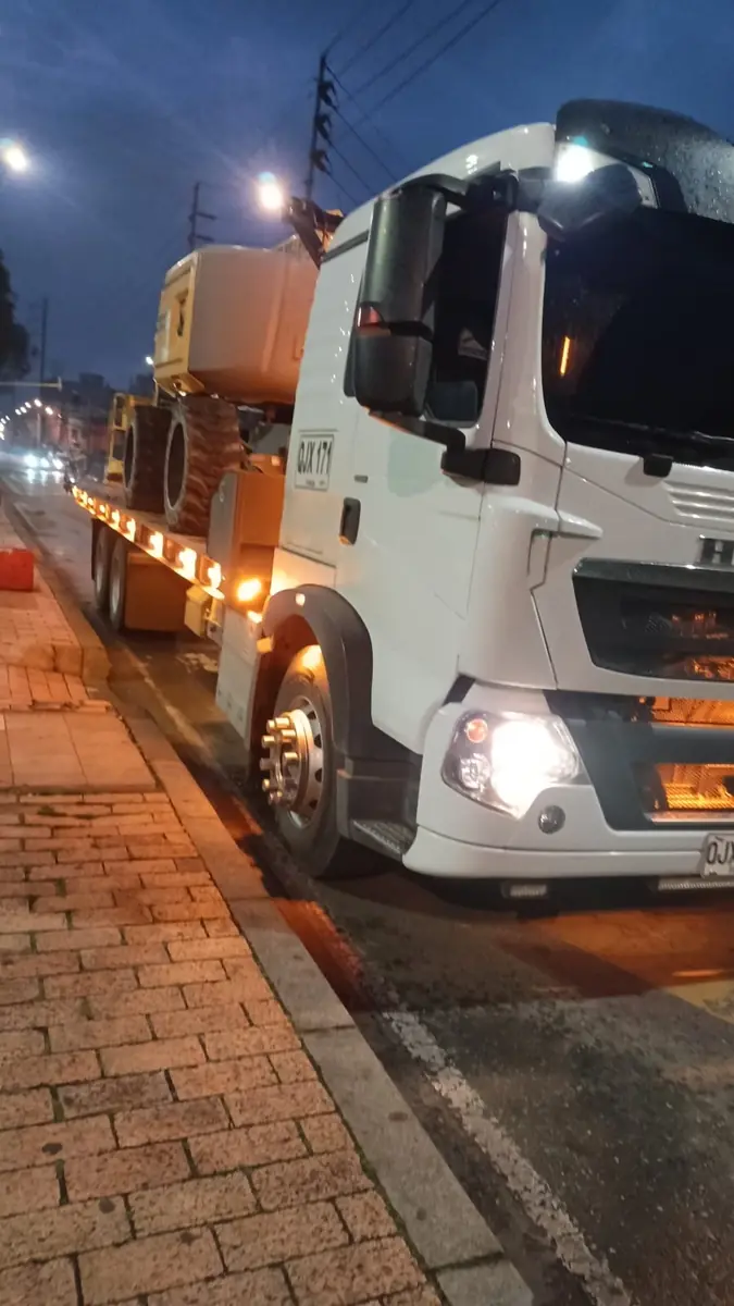 Camión con plataforma transportando un manlift de noche